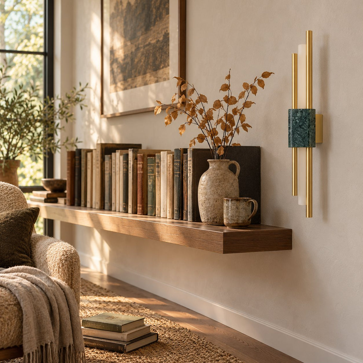 Alcochete green marble and gold wall sconce beside a wood shelf of books and a stoneware vase.