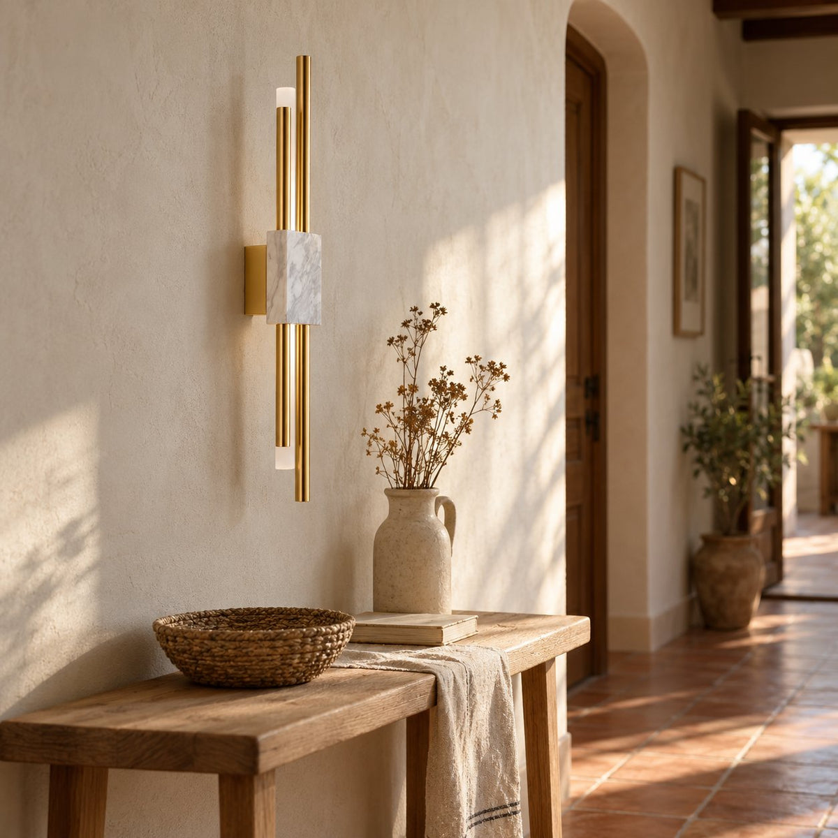Alcochete asymmetric wall sconce in brass with a marble accent above a console table.