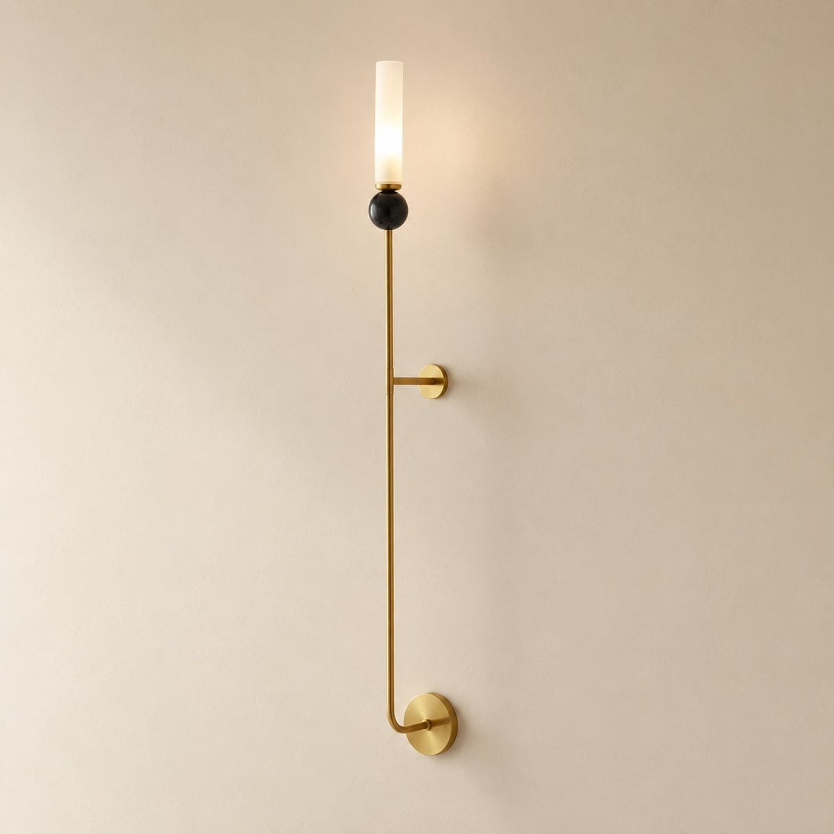 Aljezur vertical marble wall sconce in brass with black marble, Model A (36 cm), unlit, shown close on a plaster wall.