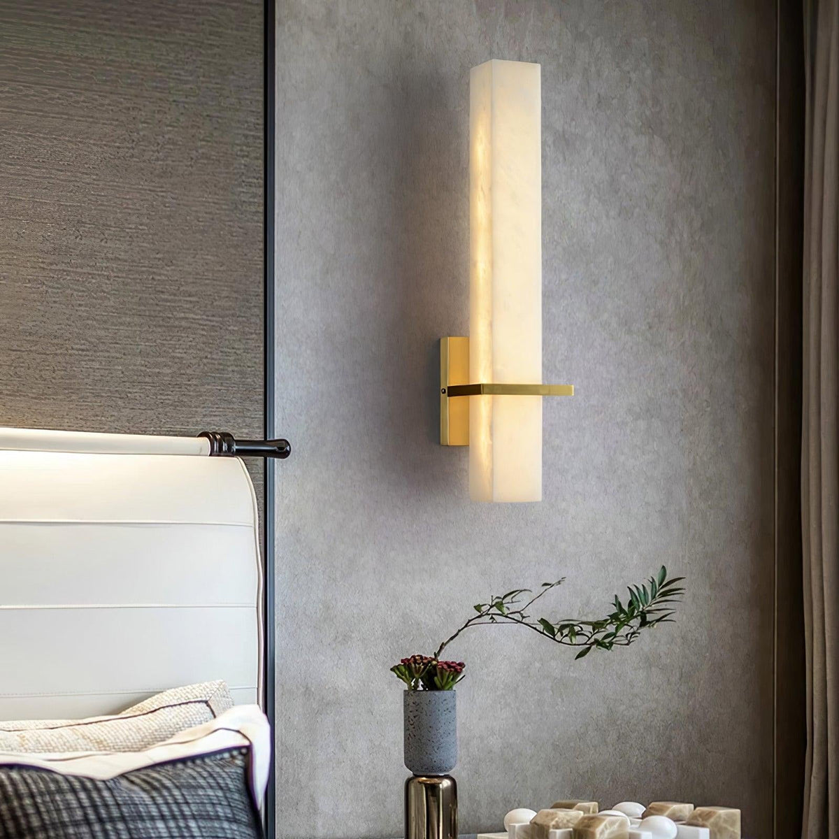 Amieira sconce mounted beside bed, casting warm light on wall