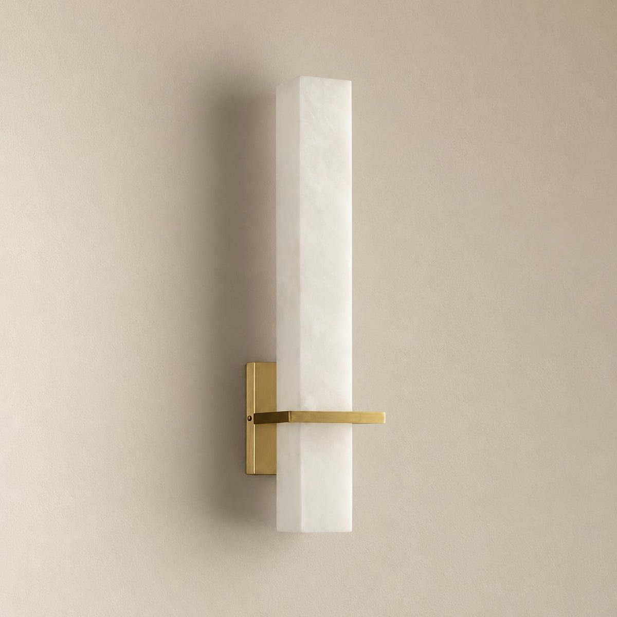 Amieira vertical alabaster wall sconce in brushed brass, unlit on a plain plaster wall.