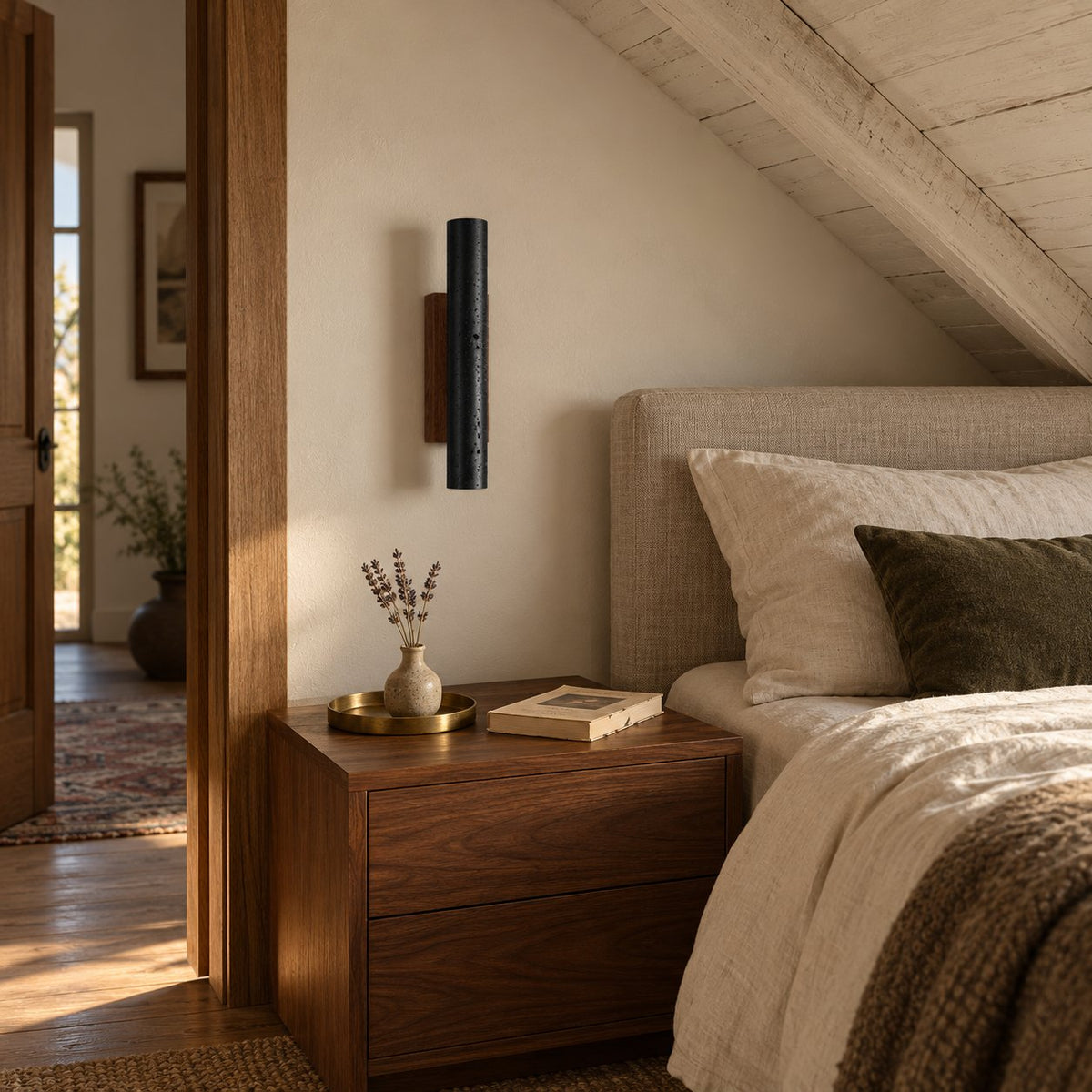 Arraiolos black travertine wall sconce with walnut back in an attic bedroom nook.