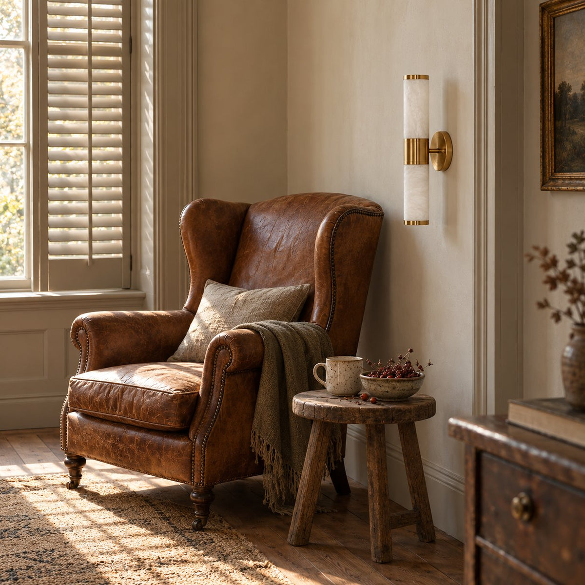Beja alabaster wall sconce with brass bands beside a brown leather armchair.