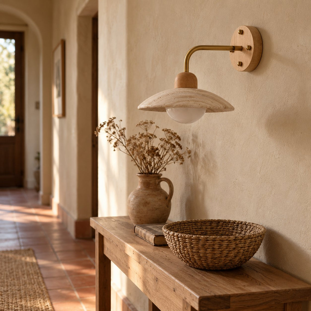Boticas travertine dome arm sconce with a brass arm above a hallway console table.