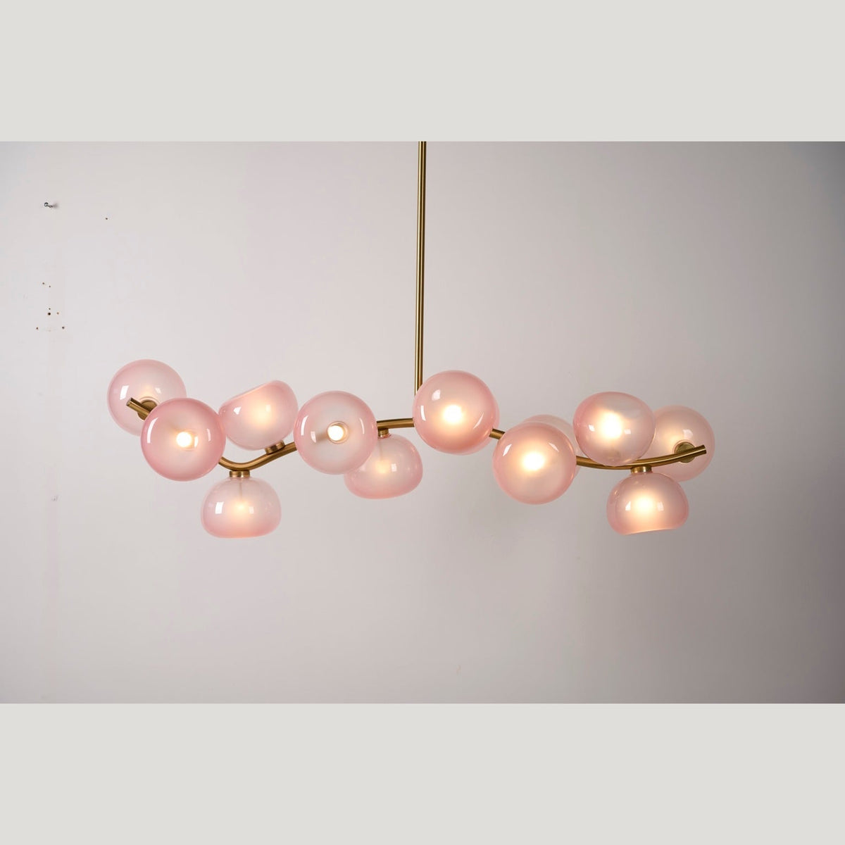 Blush glass chandelier illuminated — real product photograph