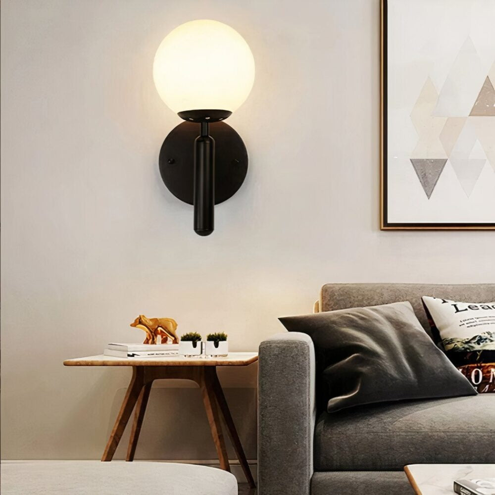 Elio globe wall sconce in black in a living room