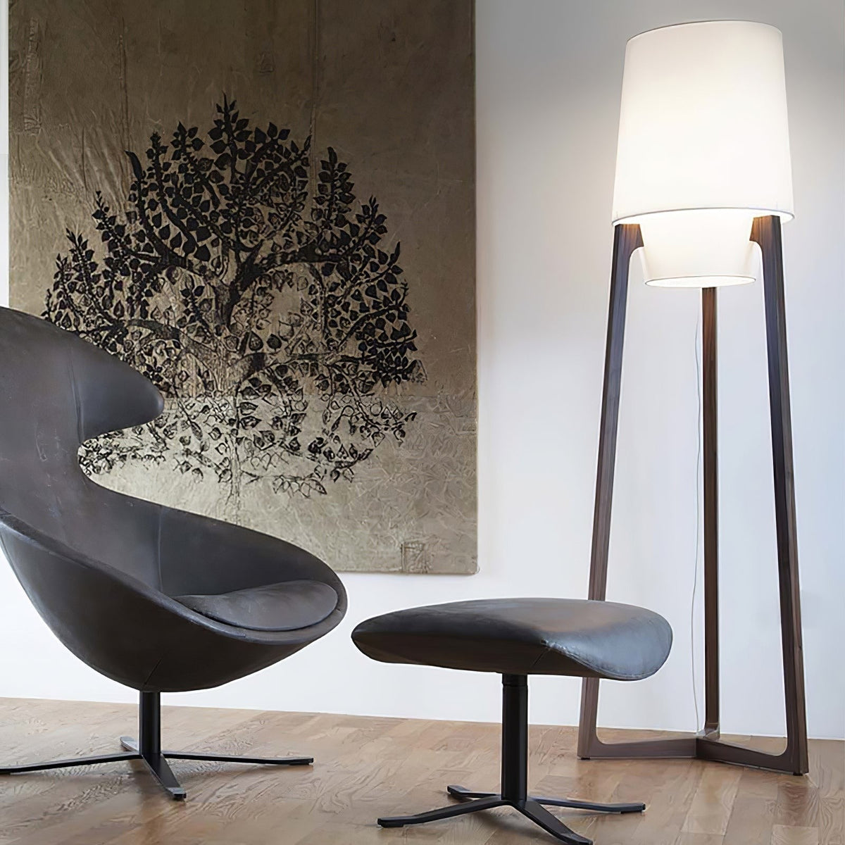 Morros floor lamp lit beside a black leather lounge chair