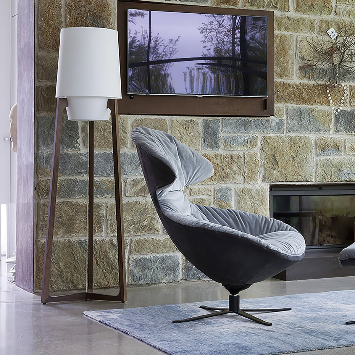Morros floor lamp lit beside a grey lounge chair and a stone wall