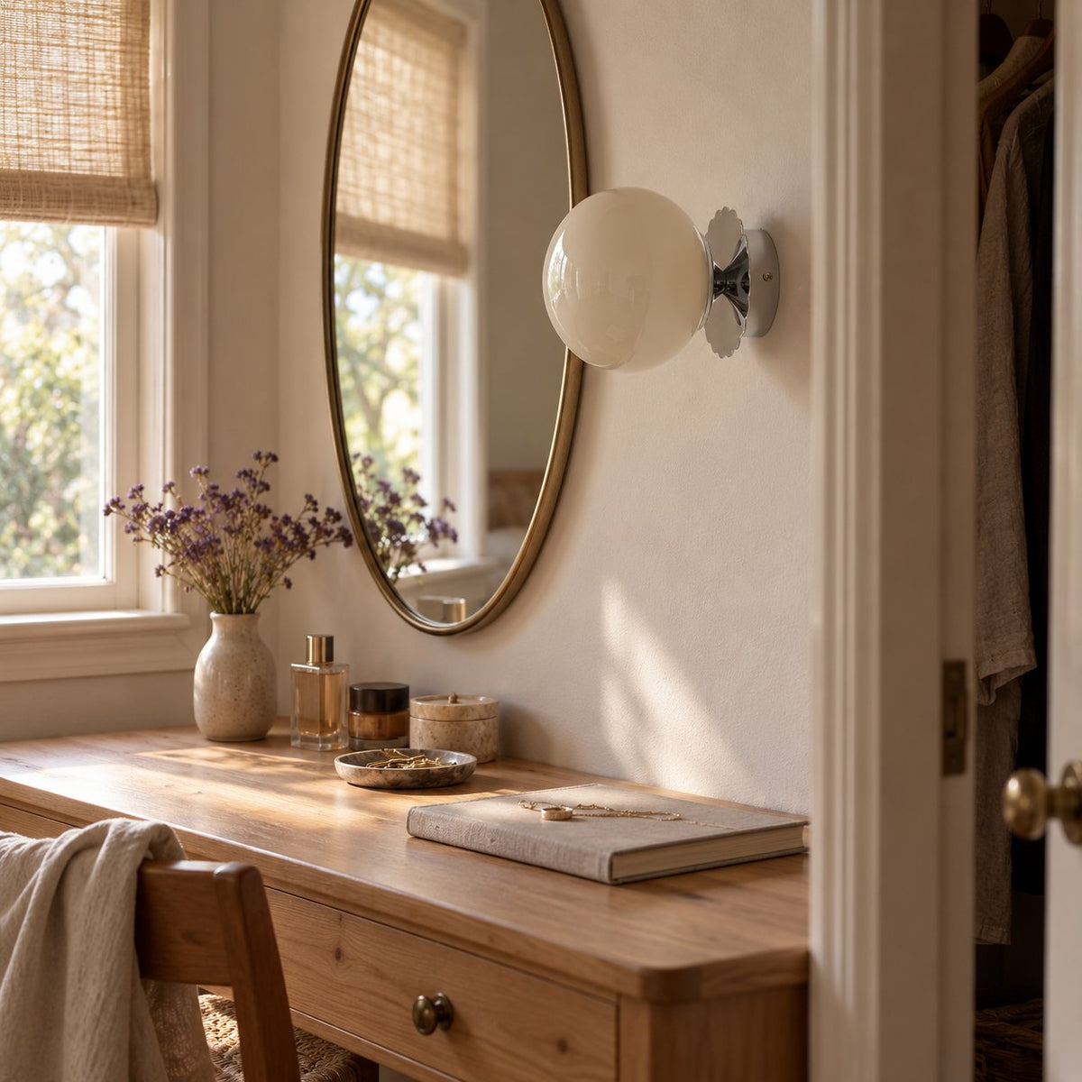 Tâmega convertible wall sconce in chrome with beige glass beside an oval mirror in a small dressing room.