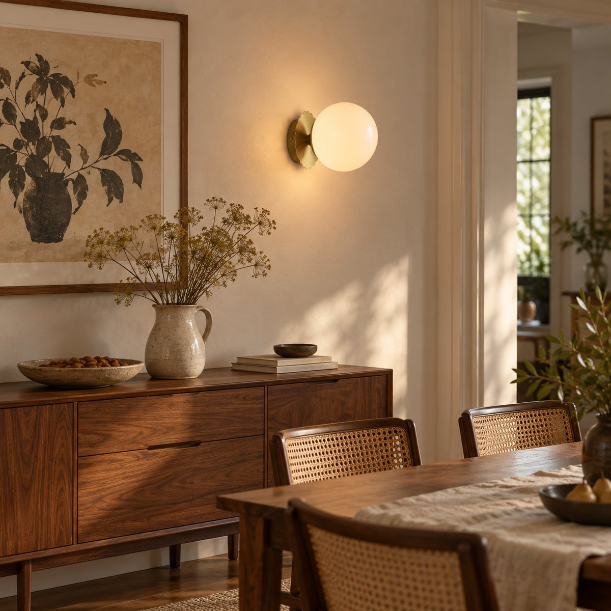 Tâmega convertible wall sconce in gold with white glass, lit above a walnut sideboard in a dining room.