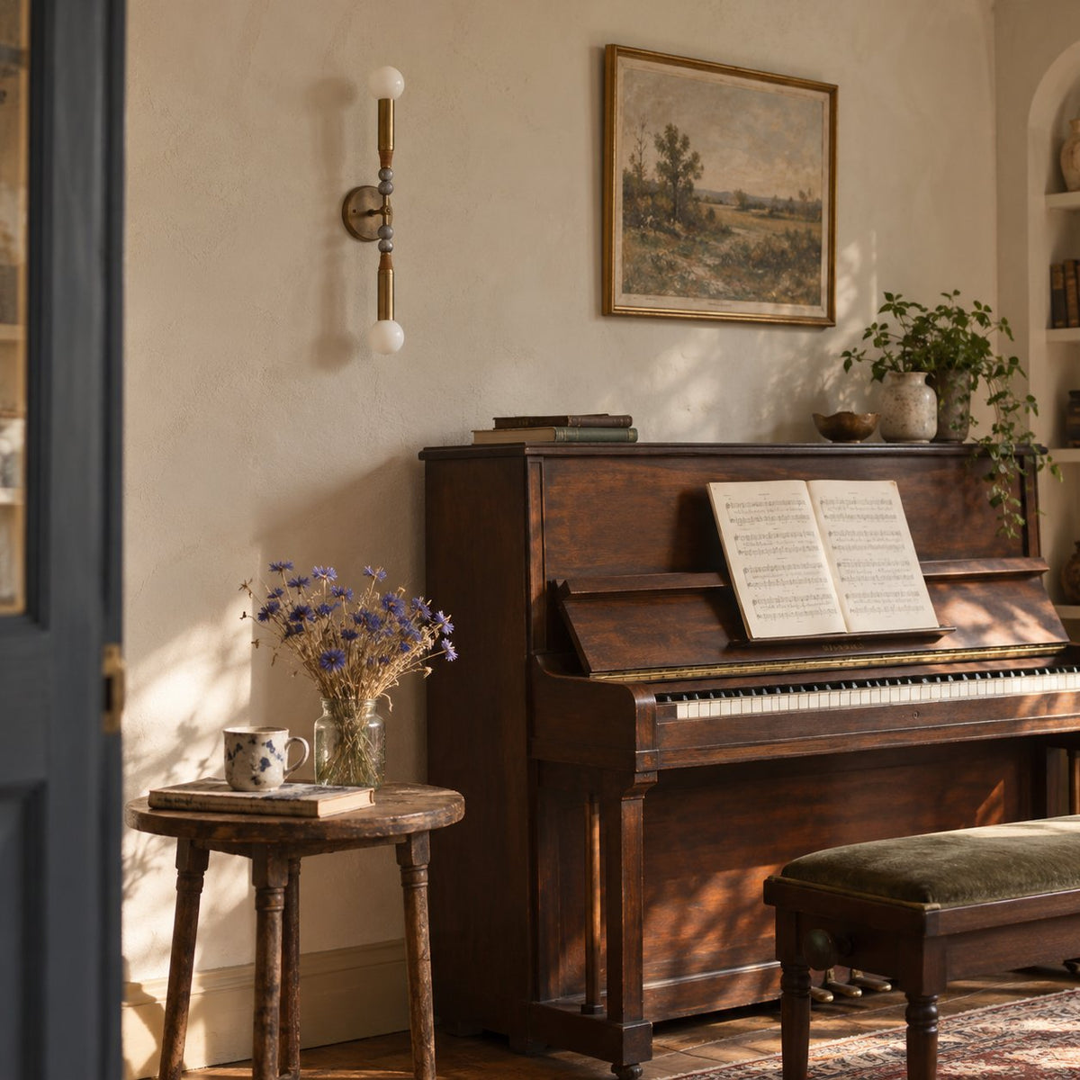 Torto wall sconce with a brass stem, marble beads, and glass globes above a piano.