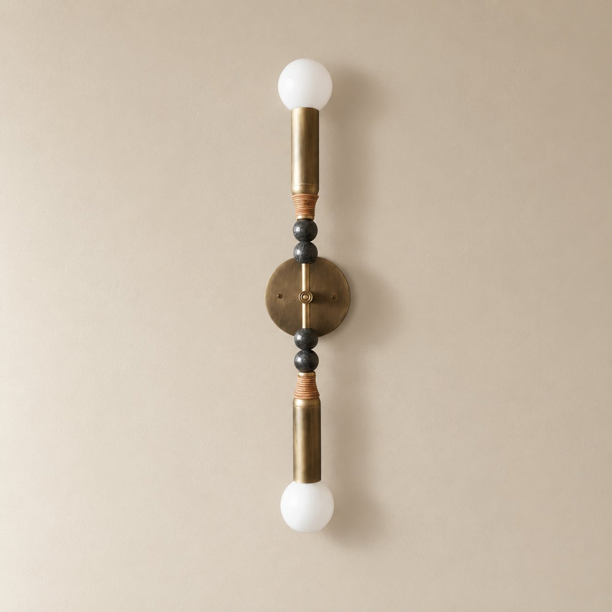 Torto marble wall sconce in antique brass and black marble, Tall (70 cm), unlit on a plain plaster wall.