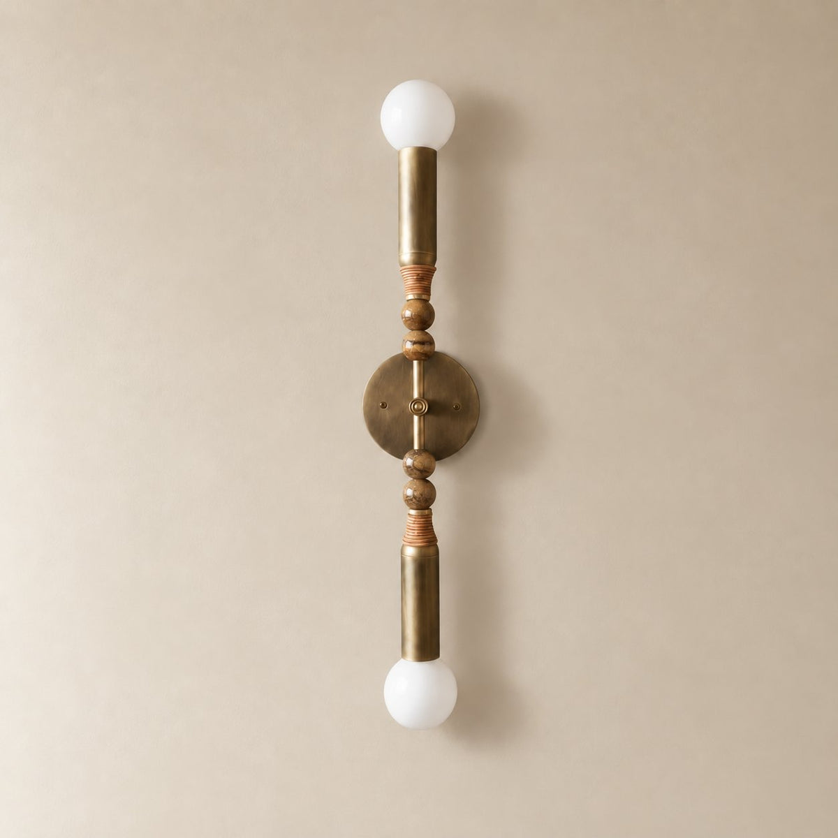 Torto marble wall sconce in antique brass and brown picture jasper, Tall (70 cm), unlit on a plain plaster wall.