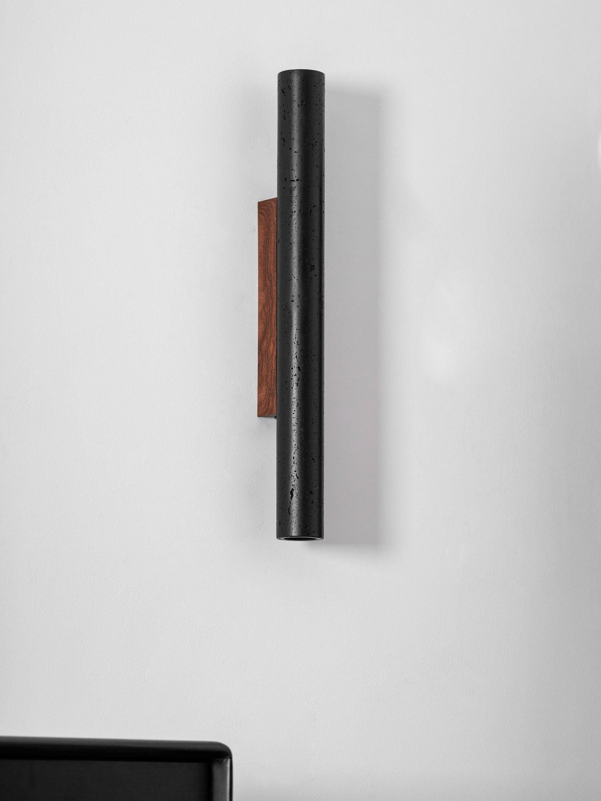 Travertine porous structure visible beneath matte black coating