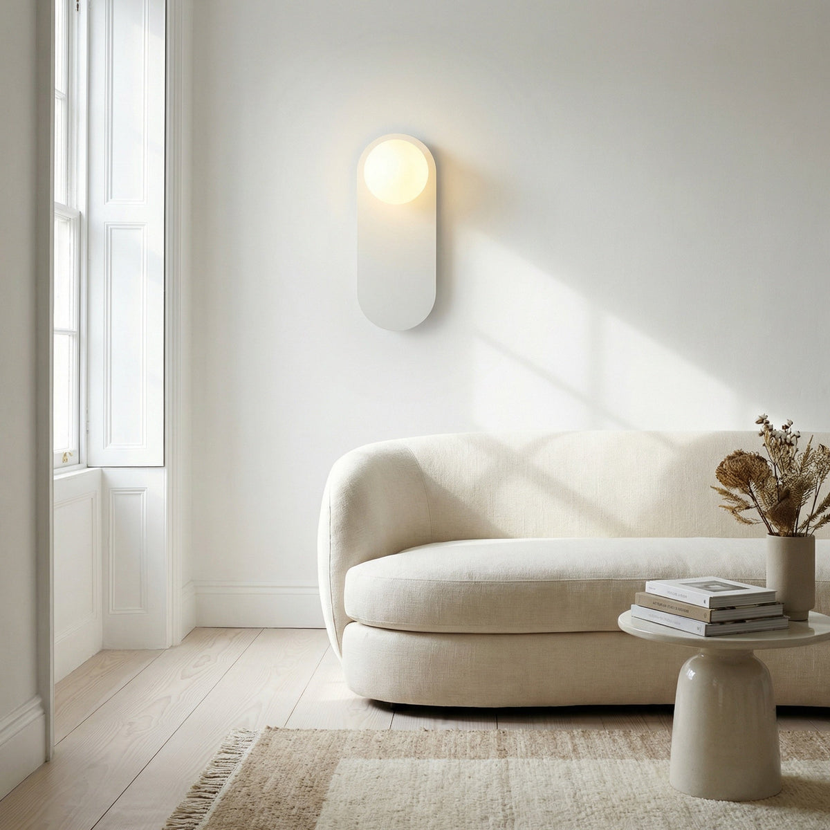 Valença wall sconce on a living room wall next to framed art and shelving