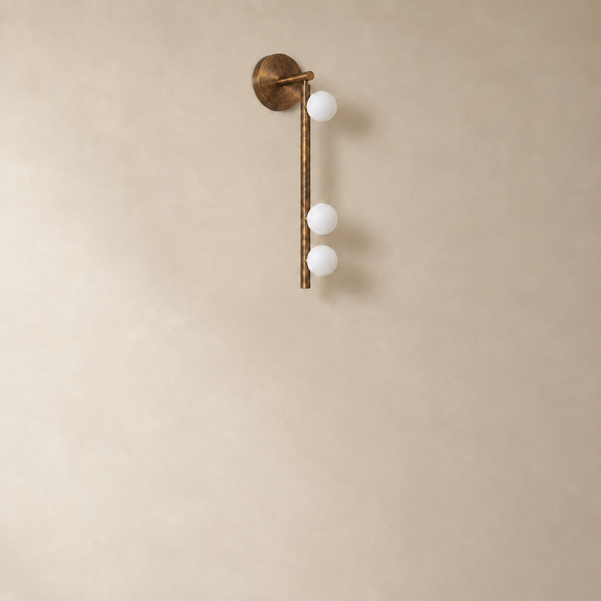 Vouga glass tube wall sconce in antique brass, 3 heads, 50 cm, unlit on a plain plaster wall.