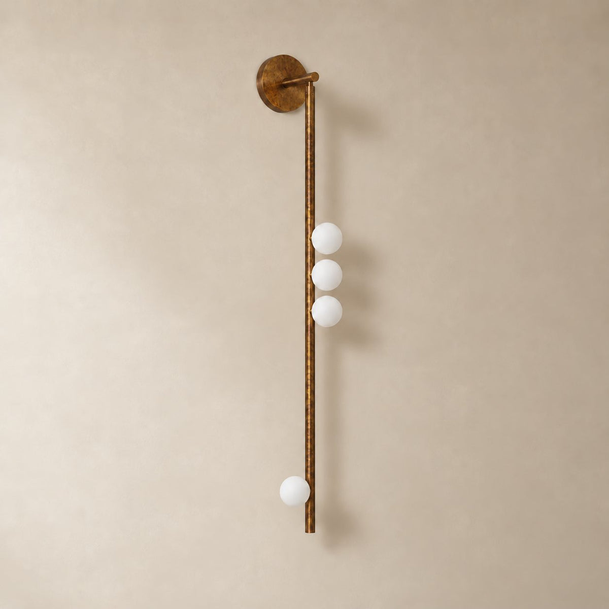 Vouga glass tube wall sconce in antique brass, 4 heads, 100 cm, unlit on a plain plaster wall.