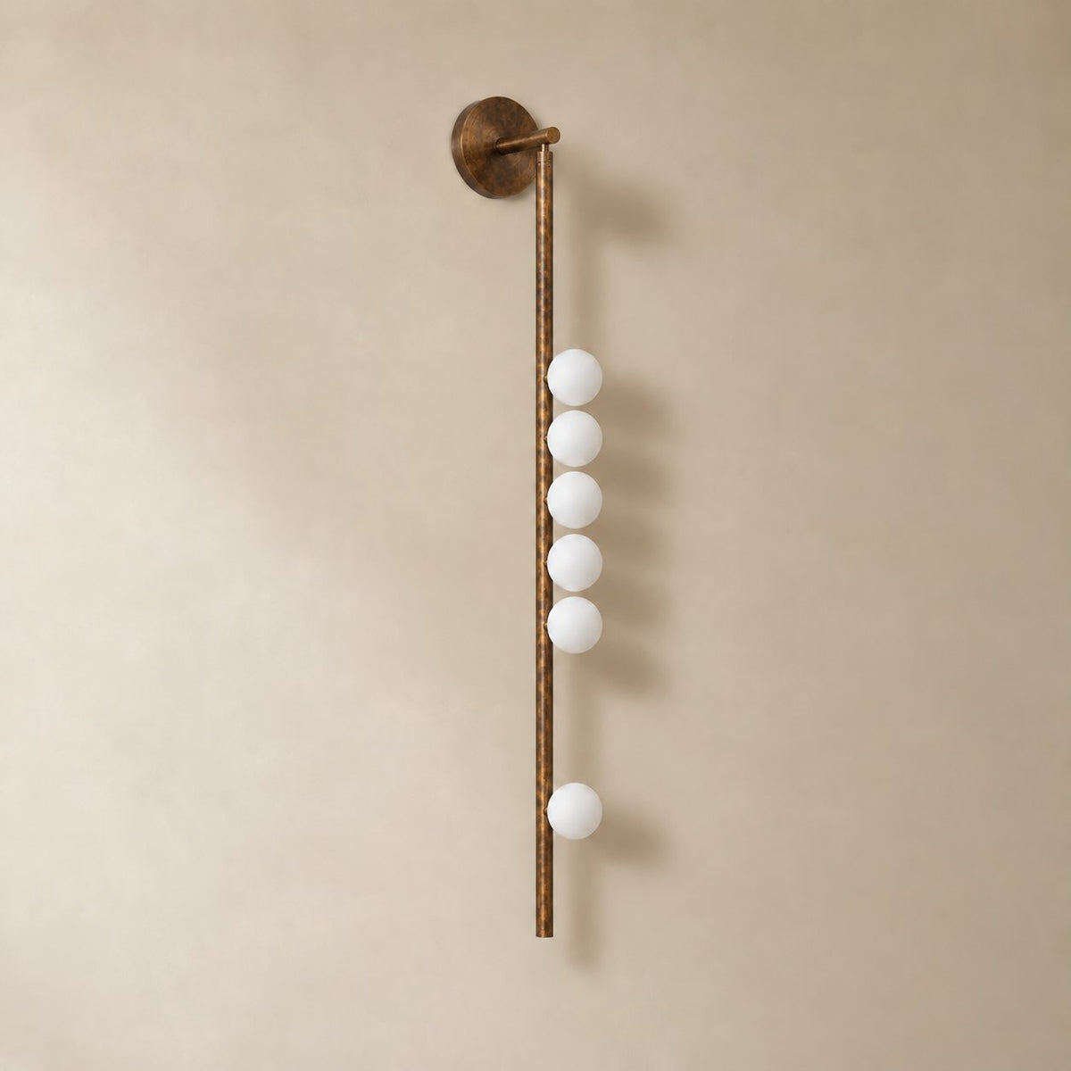 Vouga glass tube wall sconce in antique brass, 6 heads, 100 cm, unlit on a plain plaster wall.