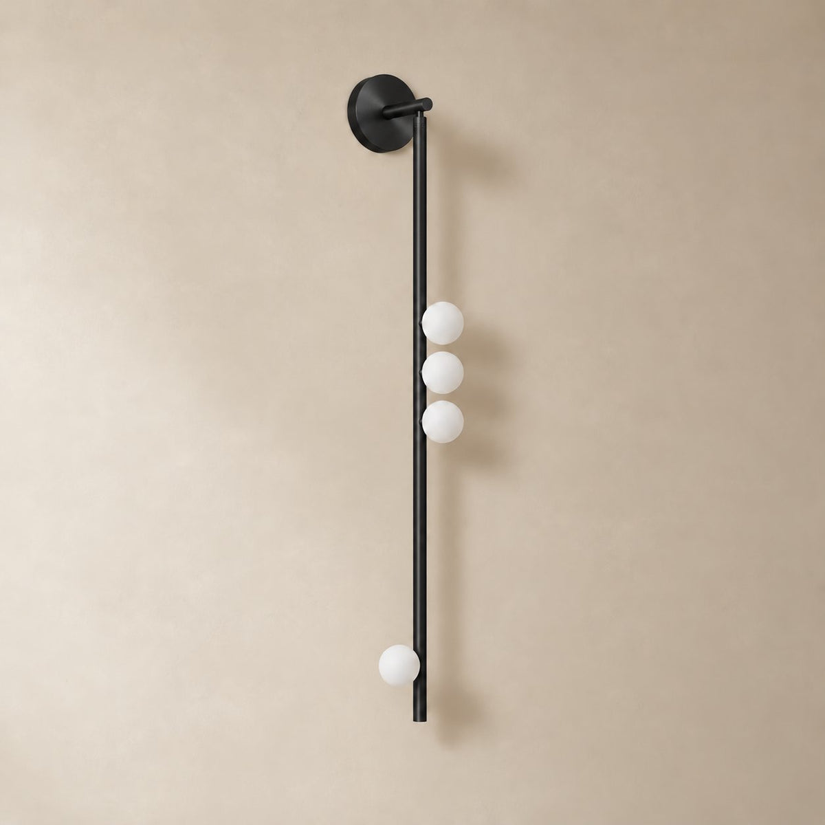 Vouga glass tube wall sconce in matte black, 4 heads, 100 cm, unlit on a plain plaster wall.