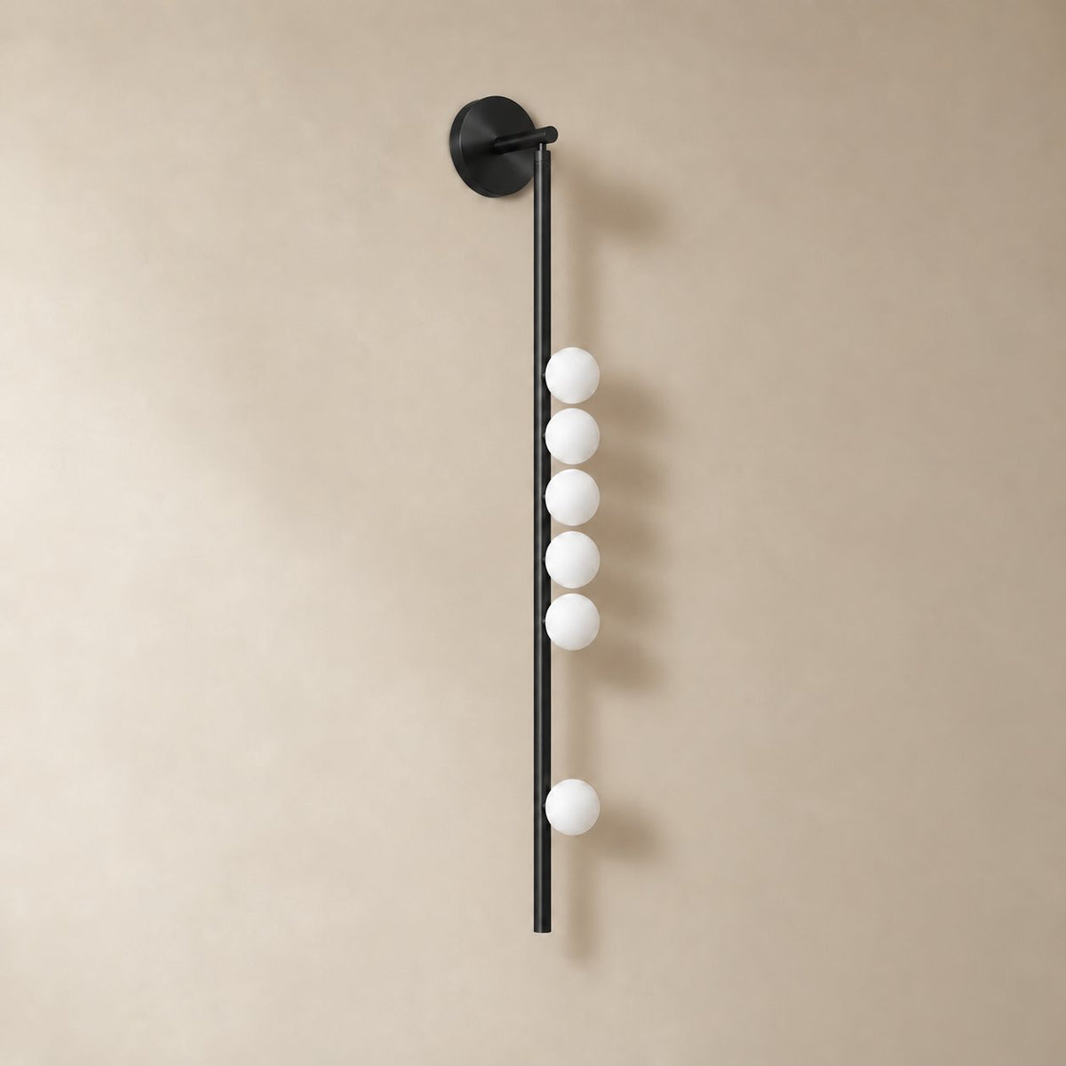 Vouga glass tube wall sconce in matte black, 6 heads, 100 cm, unlit on a plain plaster wall.