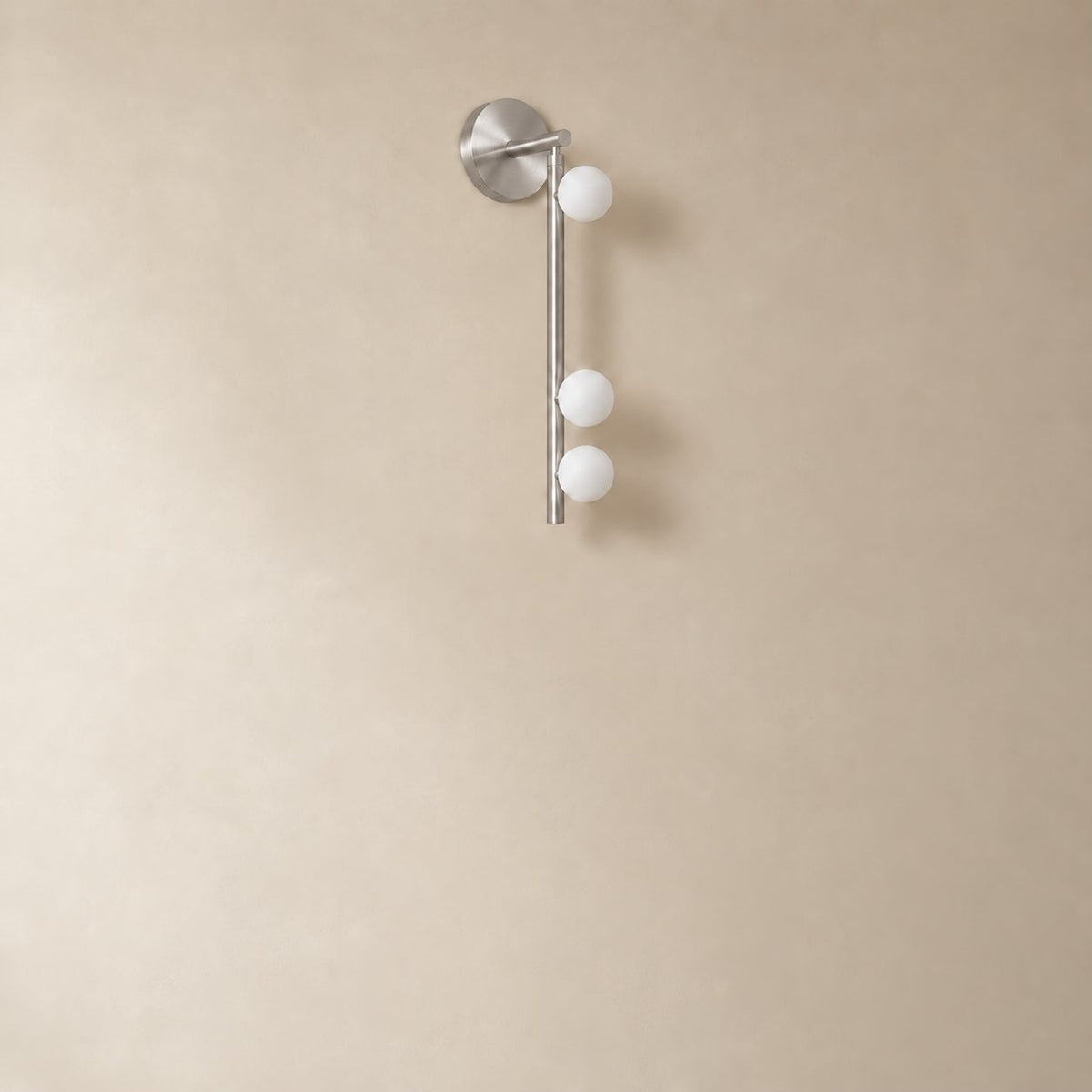 Vouga glass tube wall sconce in nickel, 3 heads, 50 cm, unlit on a plain plaster wall.
