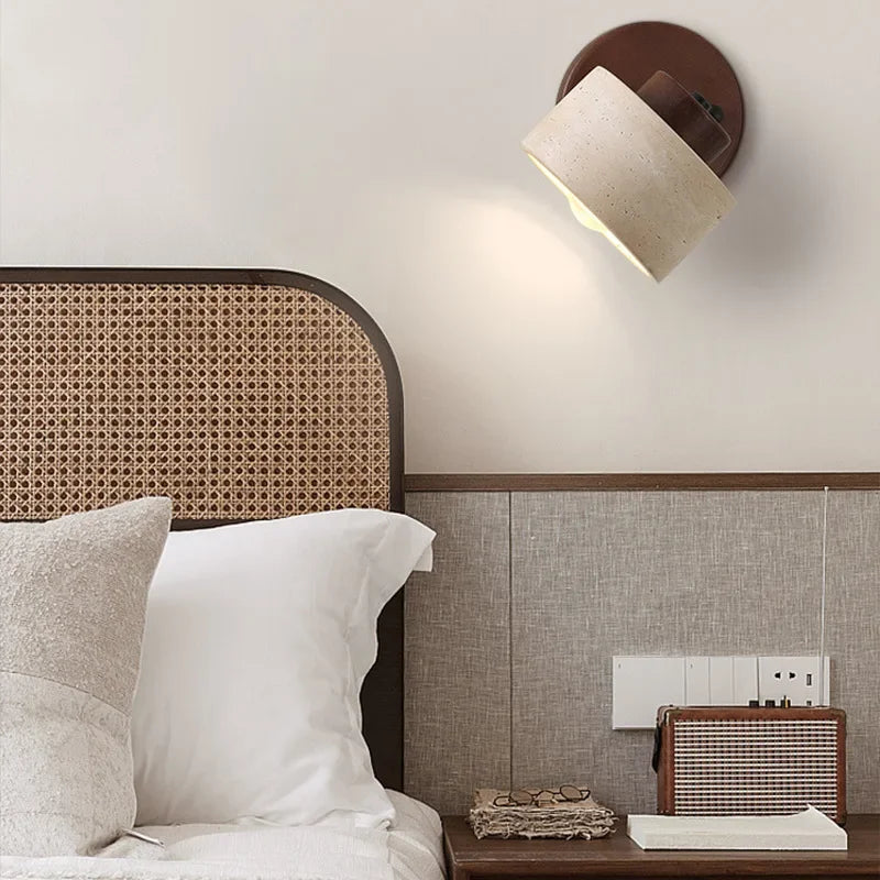 Walnut stone wall light above a rattan bed headboard, lit