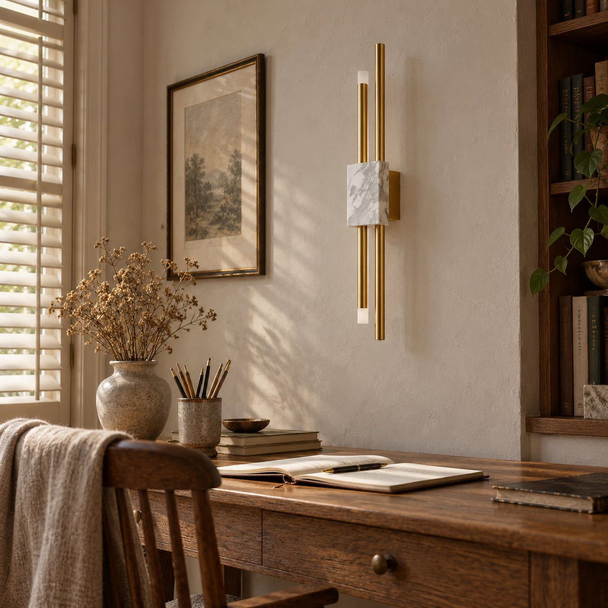 Alcochete asymmetric wall sconce with a white marble accent above a wood writing desk by a window.