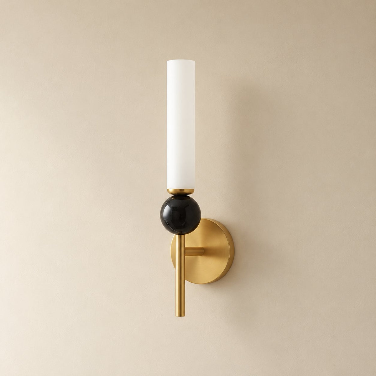 Aljezur vertical marble wall sconce in brass with black marble, Model B (38.5 cm), unlit, shown close on a plaster wall.