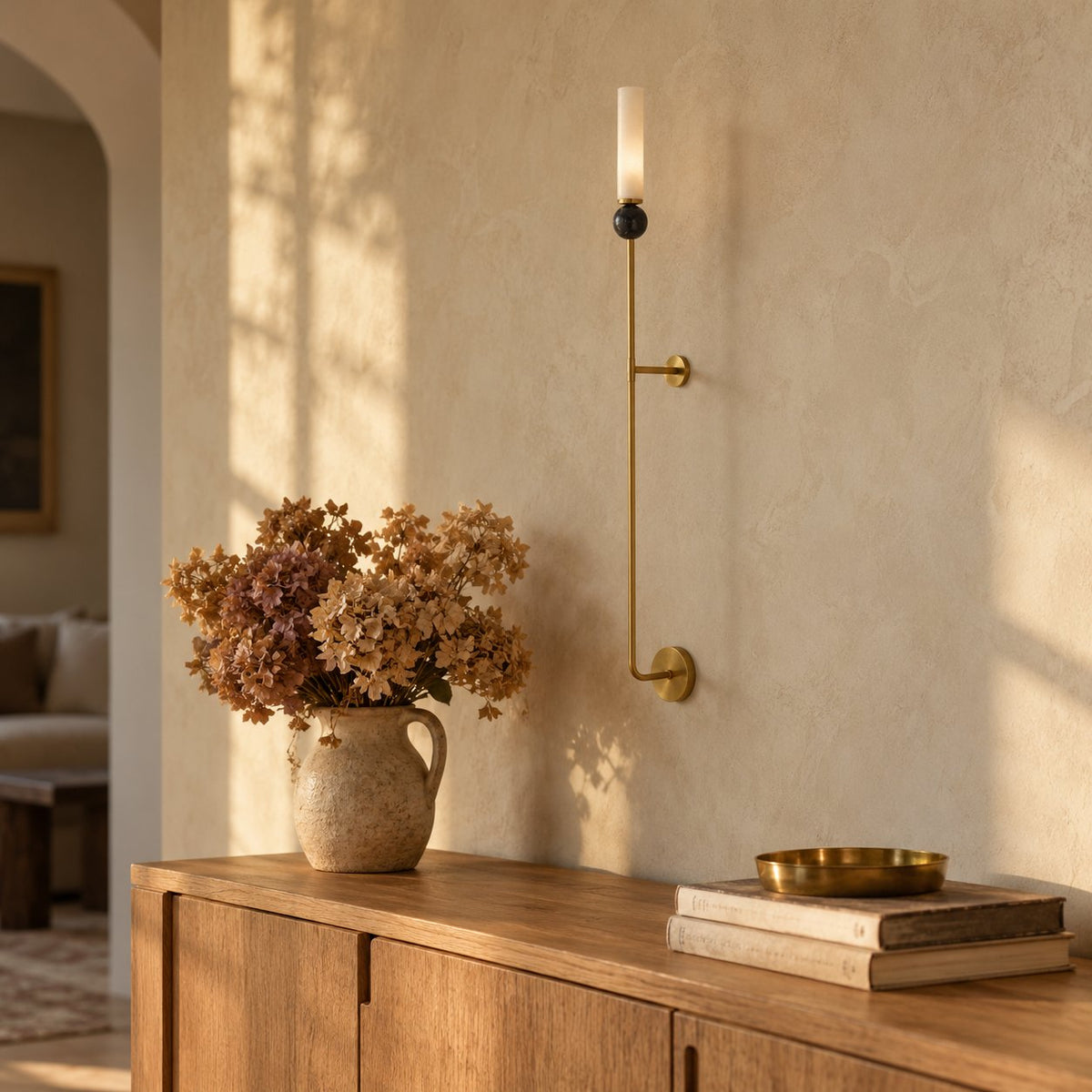 Aljezur wall sconce with white marble shade, black ball accent, above a wooden sideboard.