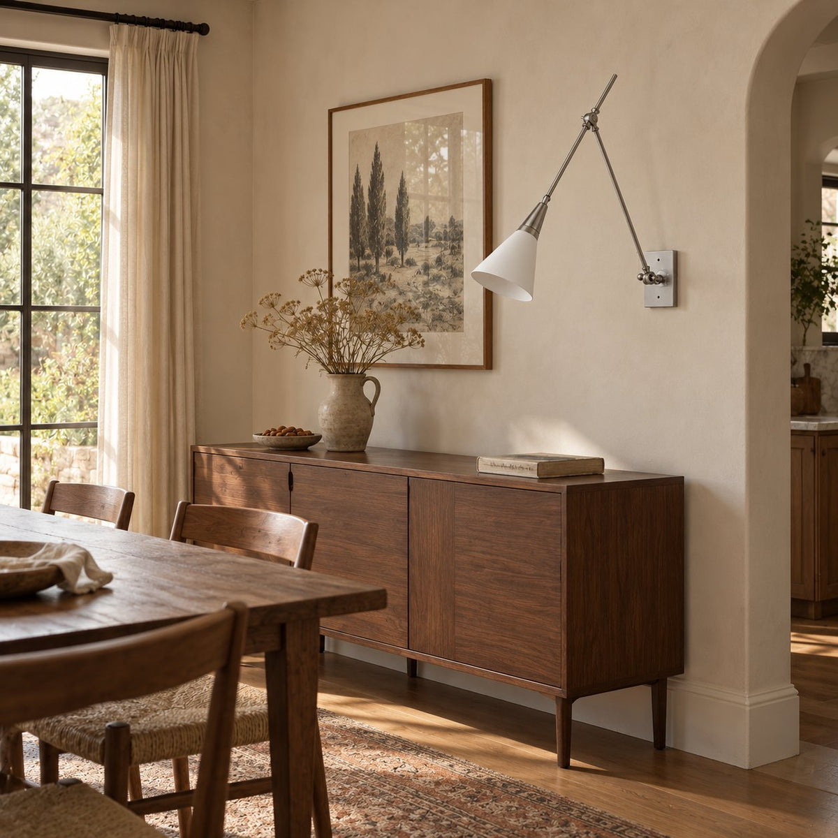 Almodôvar brushed nickel swing arm sconce with a white cone shade above a dining room sideboard.