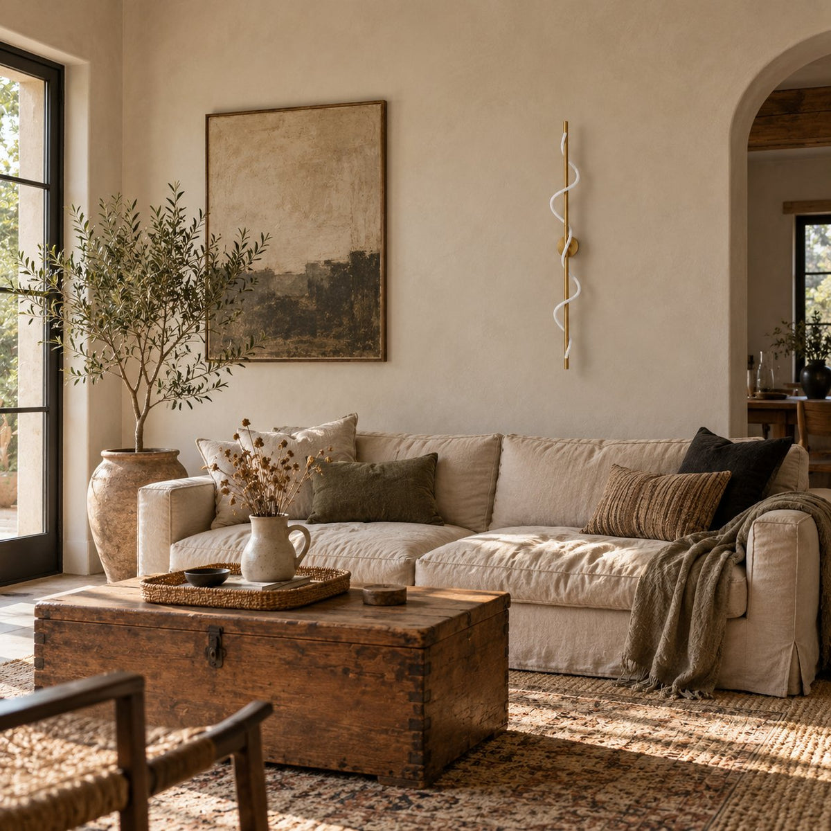 Alvito linear flexible sconce coiled around a brass rod above a linen sofa in a living room.