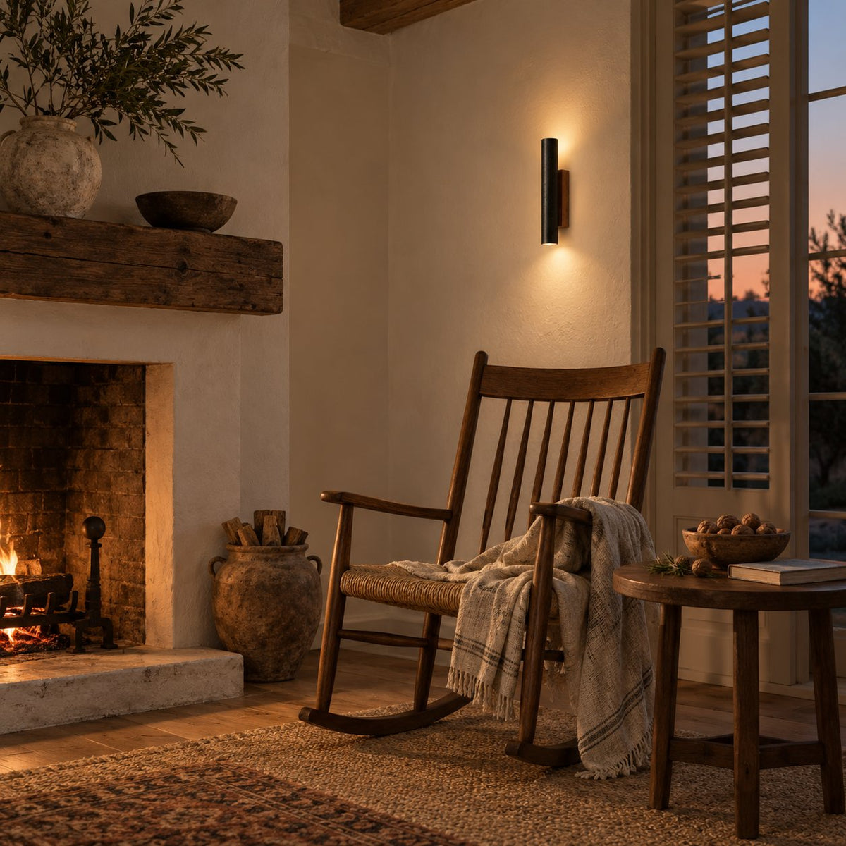 Arraiolos black travertine wall sconce with walnut back glowing by a fireplace.