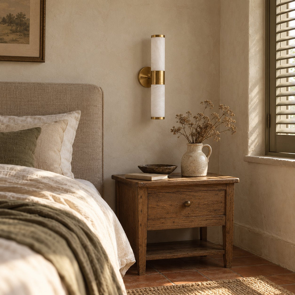 Beja alabaster wall sconce with brass bands above a bedroom nightstand.