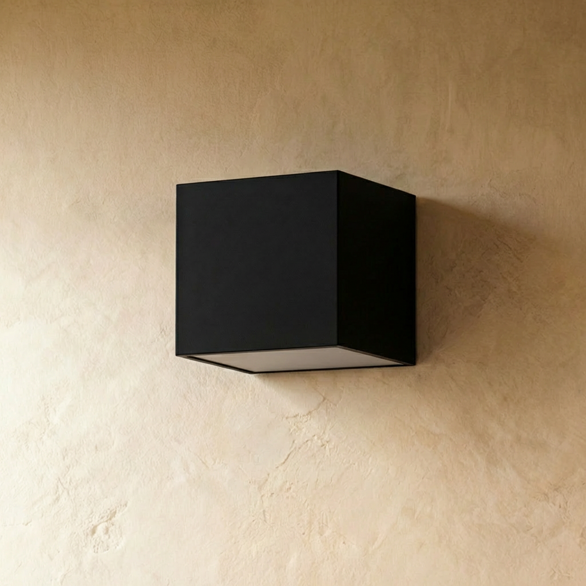 Clérachic black cube wall light, switched off, on a warm limewash plaster wall, showing its frosted diffuser at the base.
