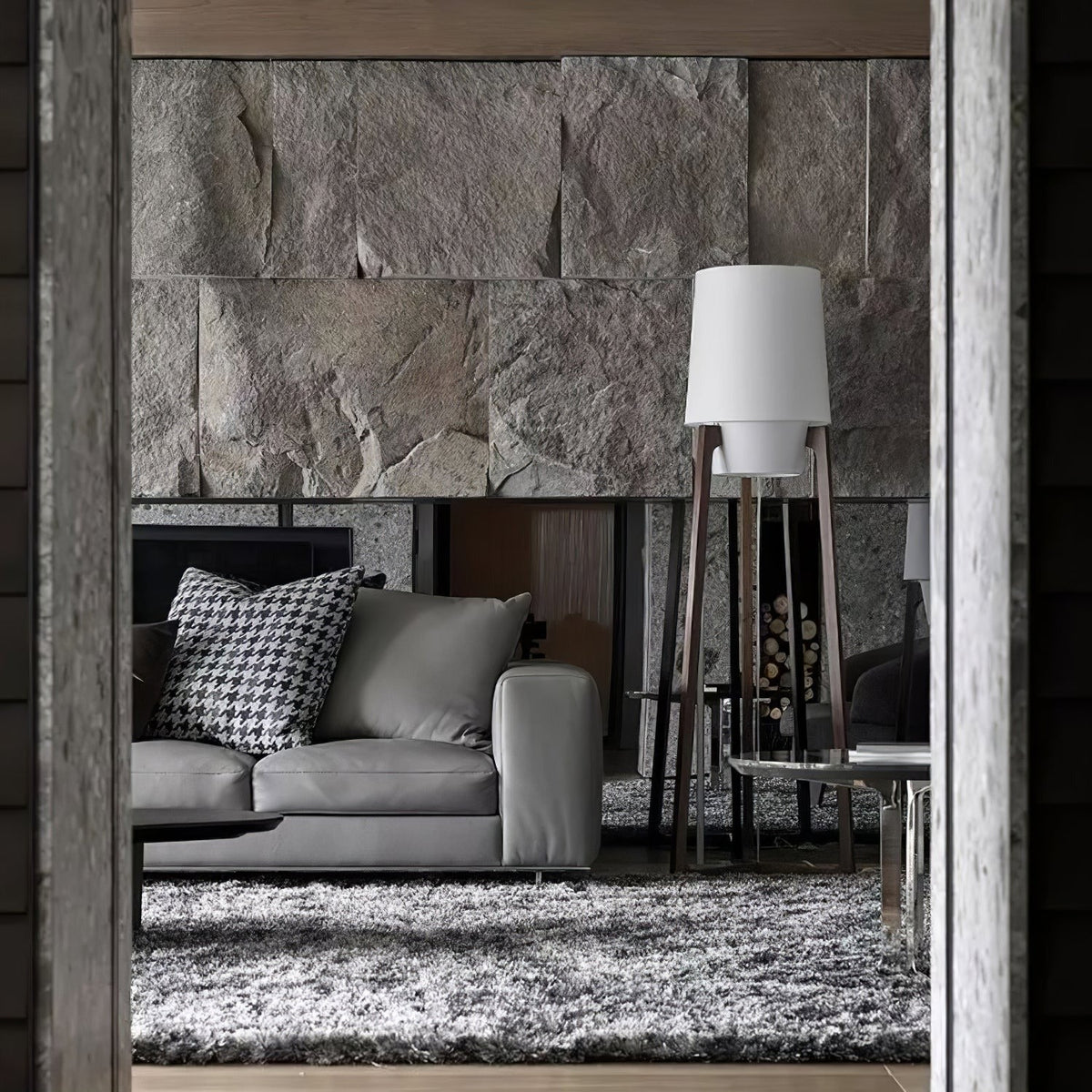 Morros floor lamp lit beside a grey sofa and a stone wall