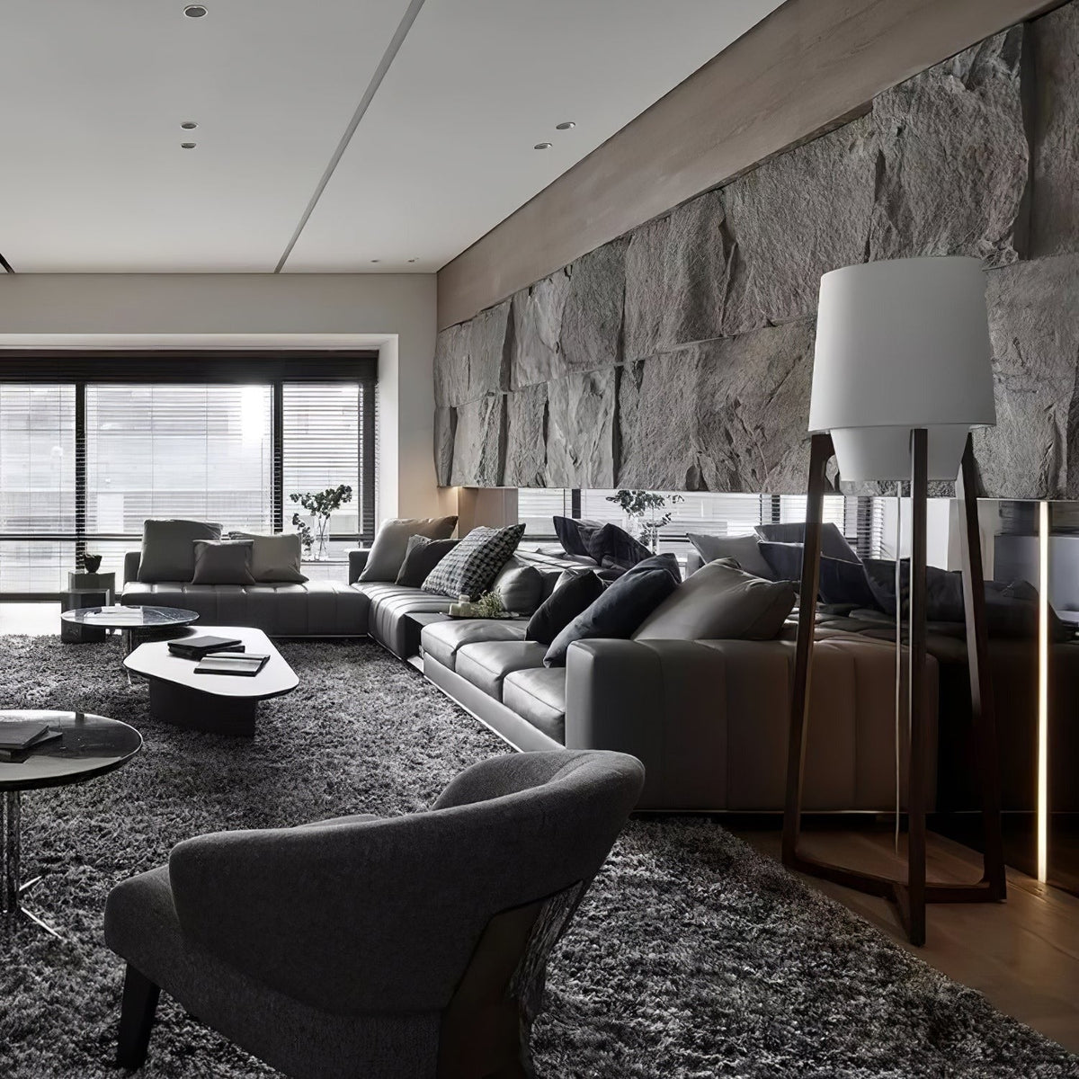 Morros floor lamp lit in a living room with a stone wall and grey sofas