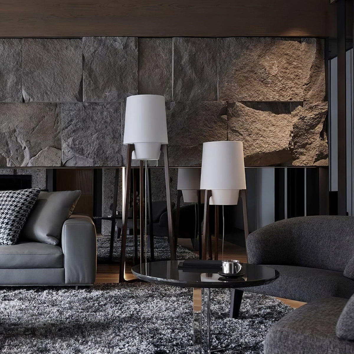 Morros floor lamps lit in a living room with a grey sofa and a stone wall