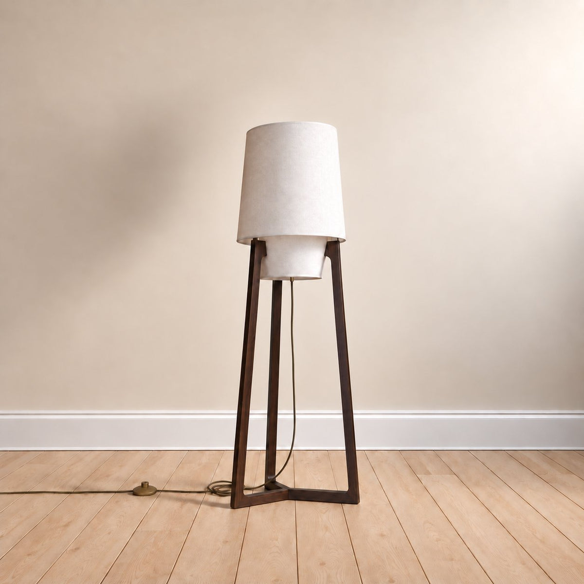 Morros tripod linen floor lamp in black walnut, the 130 cm (51.2 in) size, cord to a brass foot switch, on an oak floor.