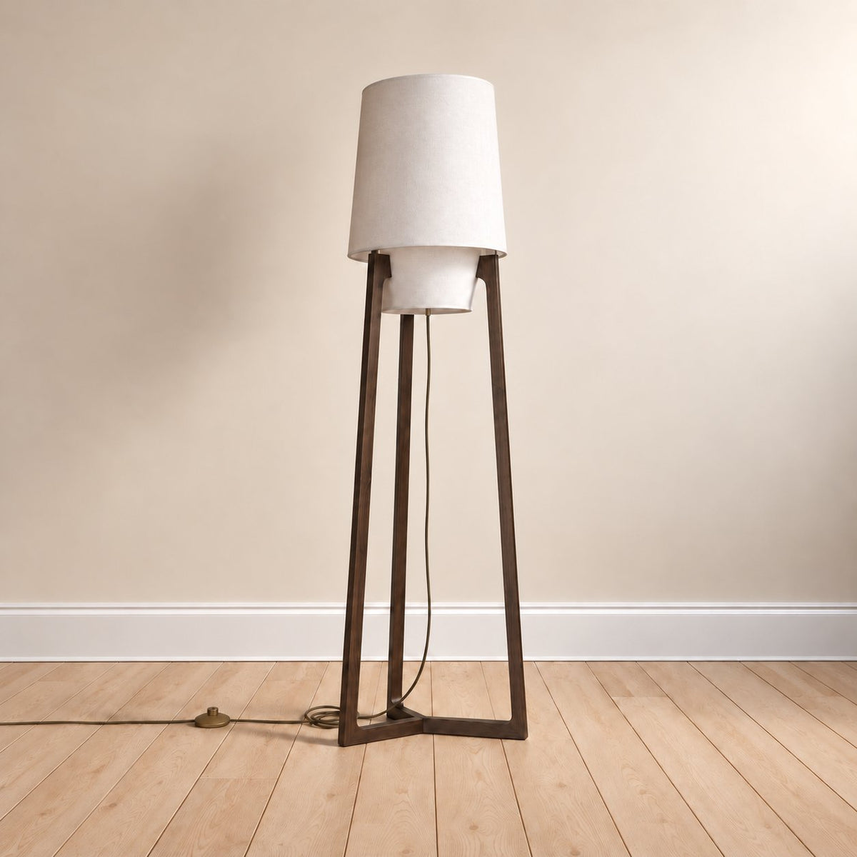 Morros tripod linen floor lamp in black walnut, the 165 cm (65 in) size, cord to a brass foot switch, on an oak floor.