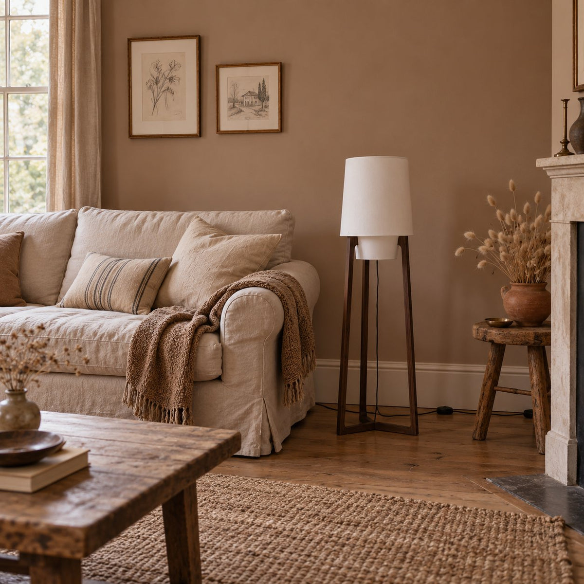 Morros tripod linen floor lamp in brown walnut beside a slipcovered sofa in a clay-painted sitting room.