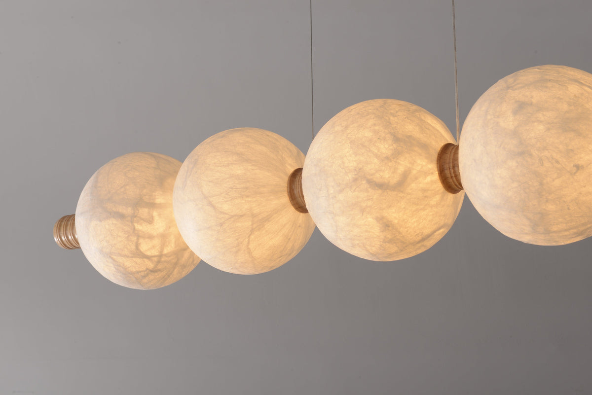Real close-up of illuminated natural mulberry silk globes, light wood central collars and suspension cables
