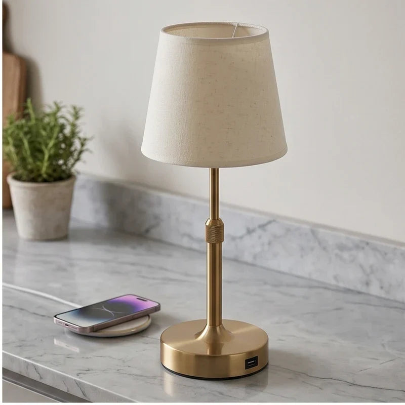 Gold cordless table lamp with off-white fabric shade, showing the USB-C charging port