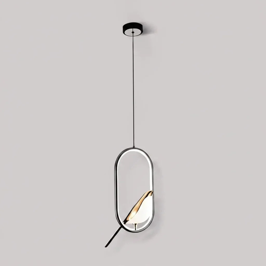 Black oval frame bird pendant with a gold accented bird against a pale gray wall