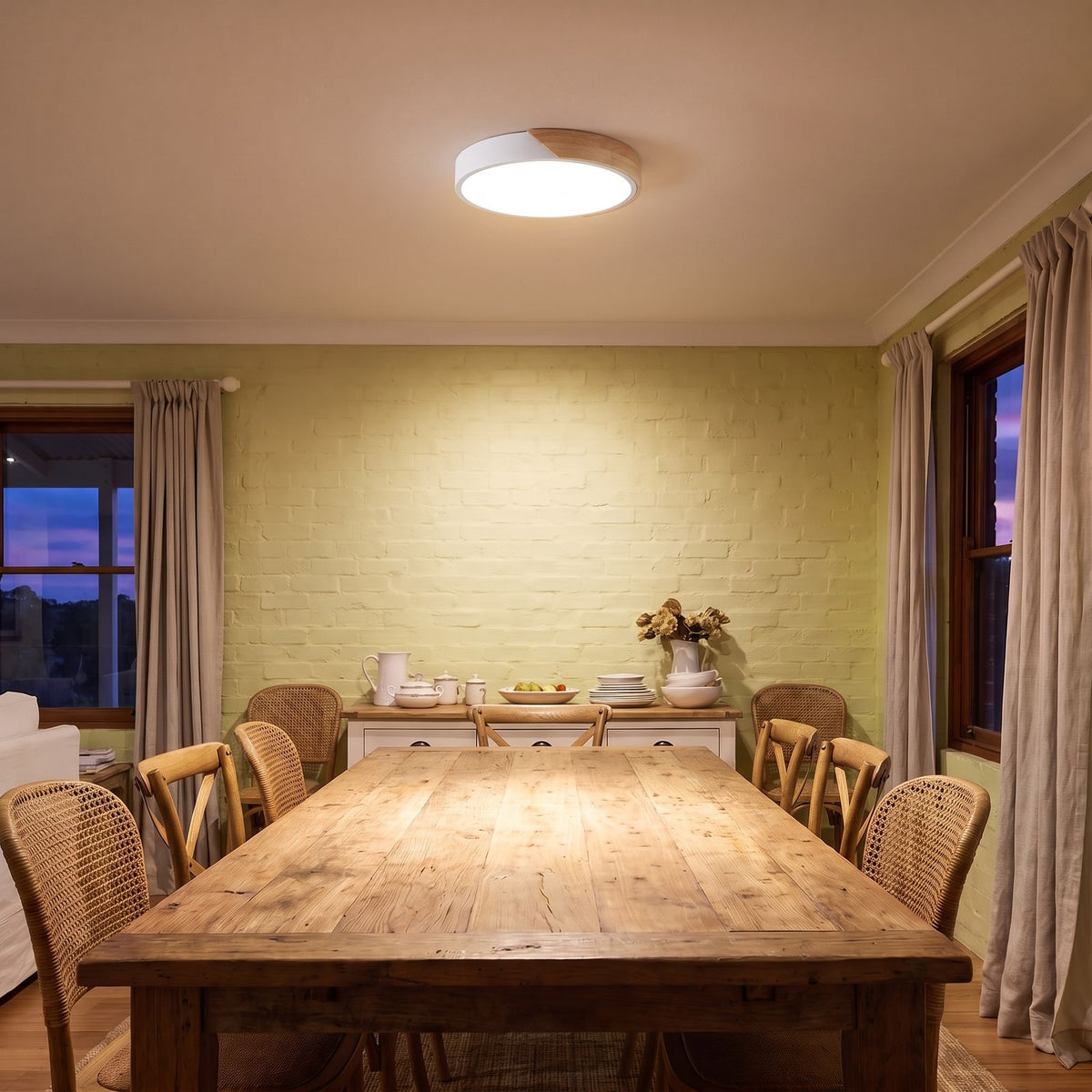 Ultra thin LED oyster ceiling light lighting a timber dining table in a country farmhouse at dusk