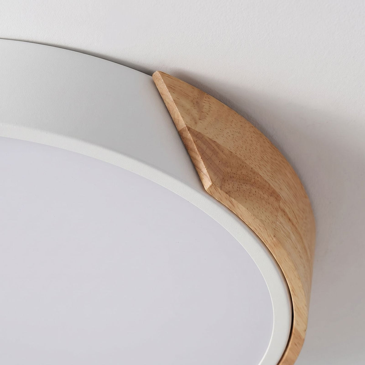Close view of the wood toned wedge meeting the painted rim of the ultra thin LED oyster ceiling light