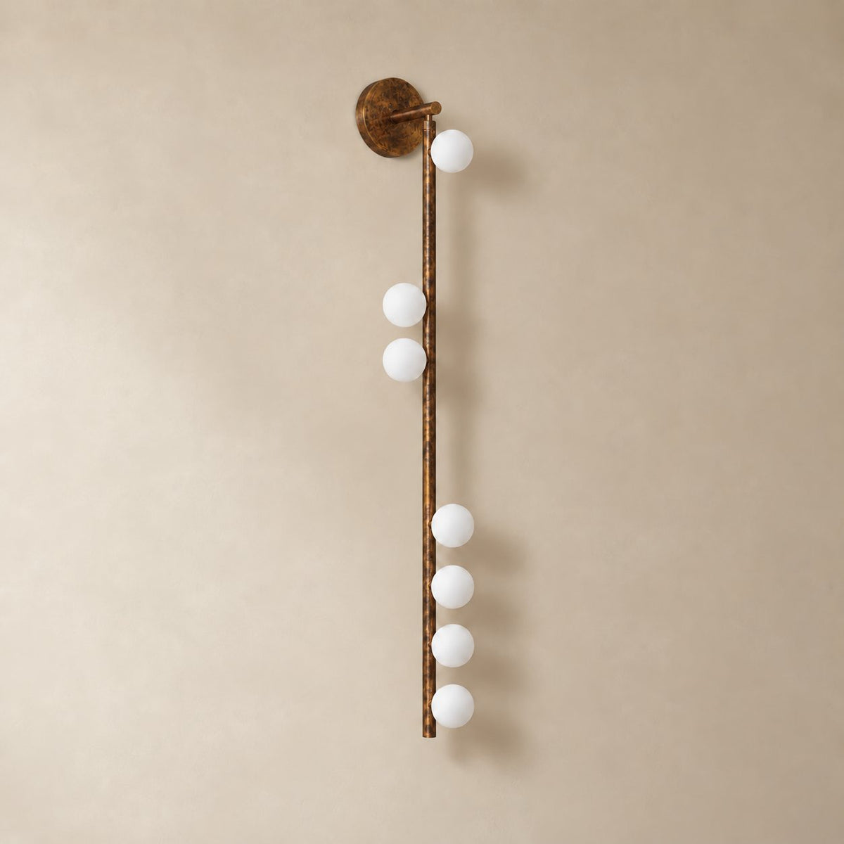 Vouga glass tube wall sconce in antique brass, 7 heads A, 100 cm, unlit on a plain plaster wall.