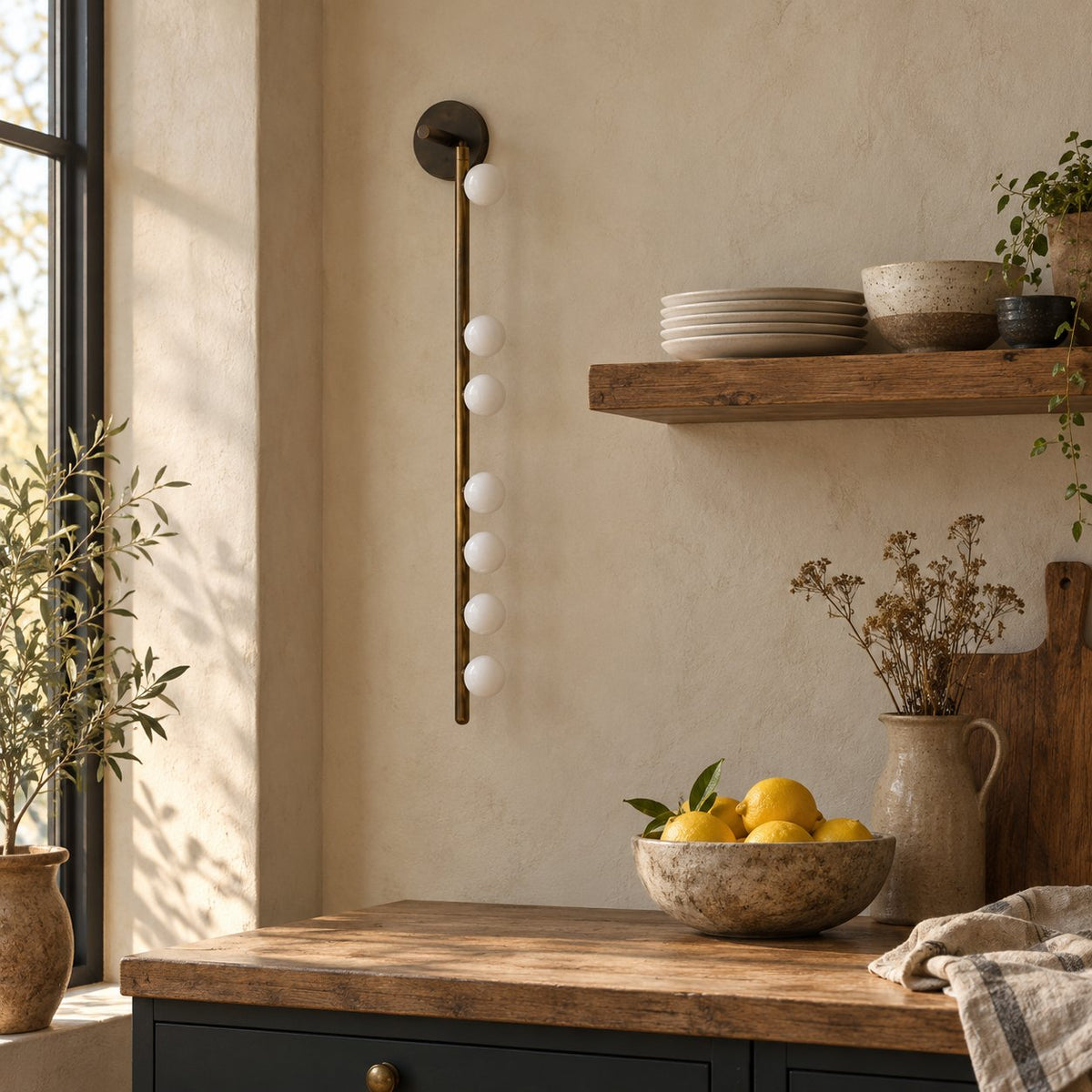 Vouga wall sconce, a brass vertical bar with small white glass globes, in a farmhouse kitchen.