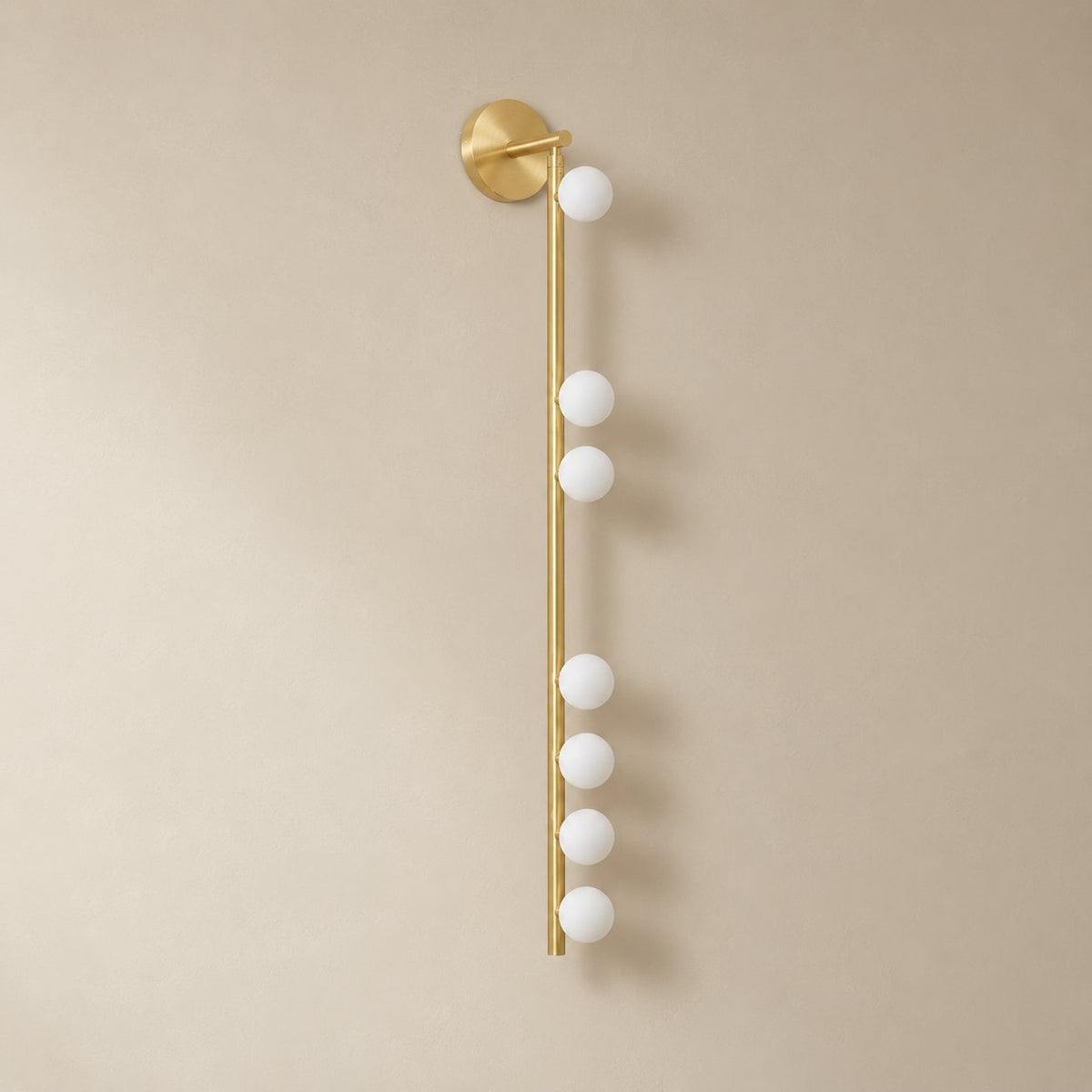 Vouga glass tube wall sconce in brushed brass, 7 heads B, 100 cm, unlit on a plain plaster wall.