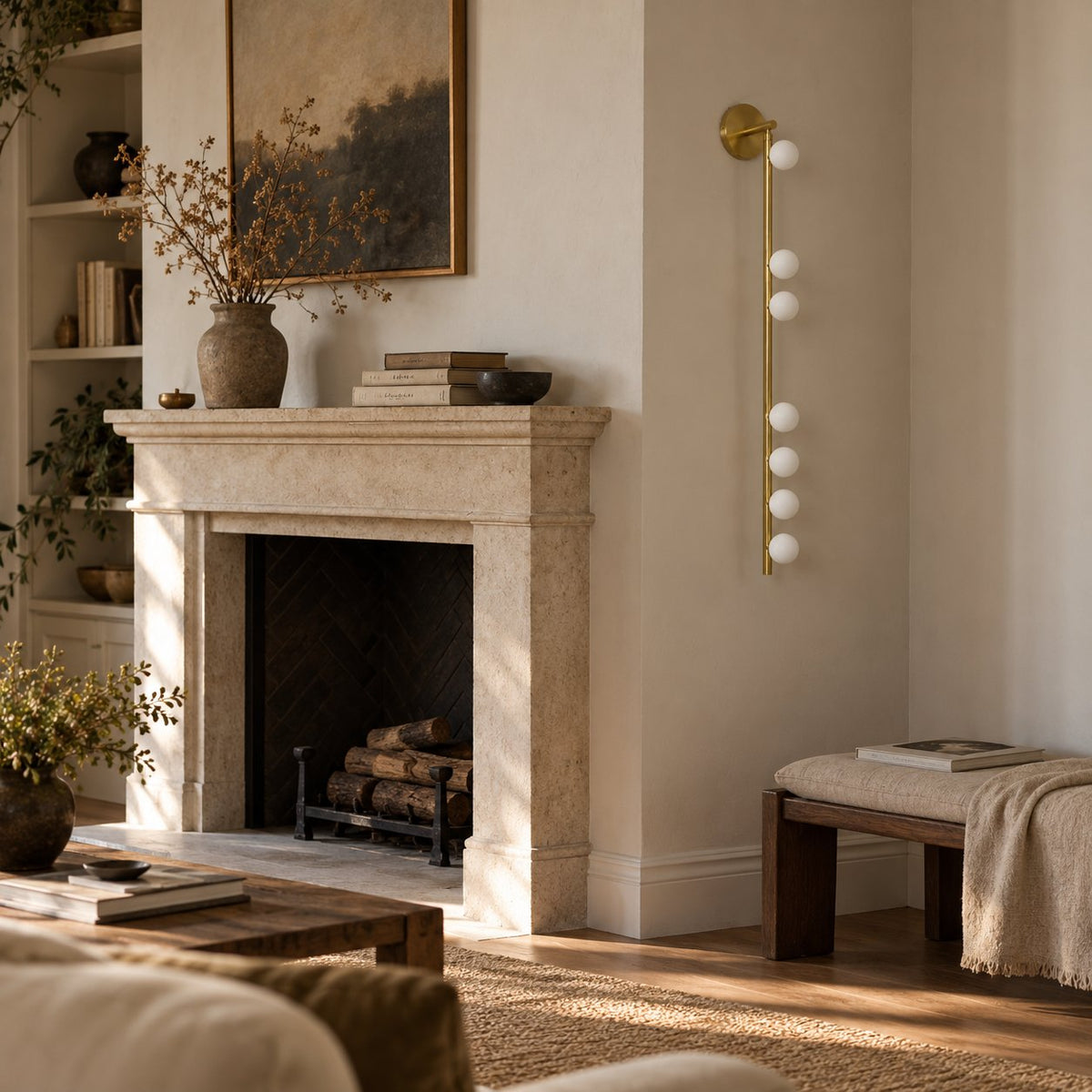 Vouga wall sconce, a brass vertical bar with small white glass globes, beside a living room fireplace.