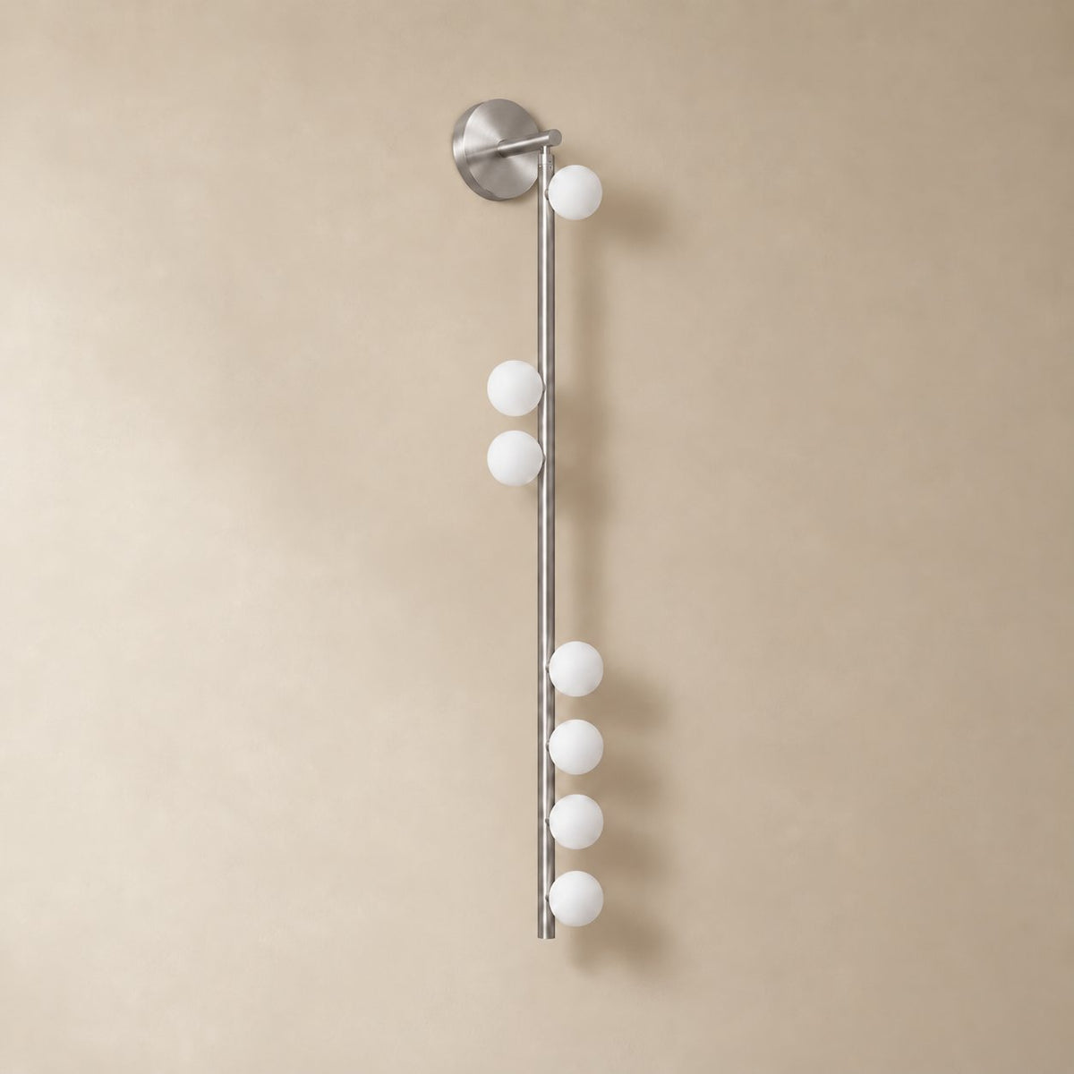 Vouga glass tube wall sconce in brushed nickel, 7 heads A, 100 cm, unlit on a plain plaster wall.